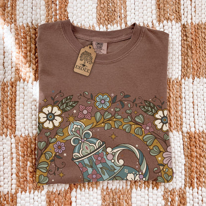 Brown t-shirt with floral and teapot design on a checkered fabric background